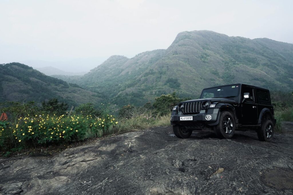 A black SUV parked on rugged terrain with mountain view, ideal for off-road adventures.