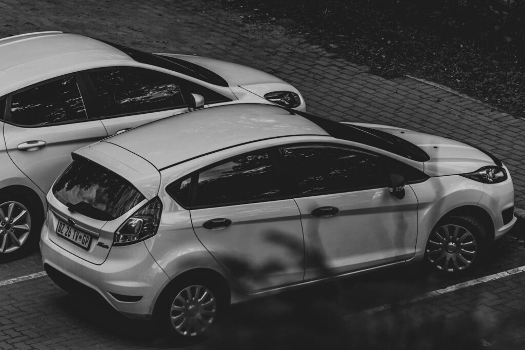 A monochrome image showcasing parked cars in an urban environment.