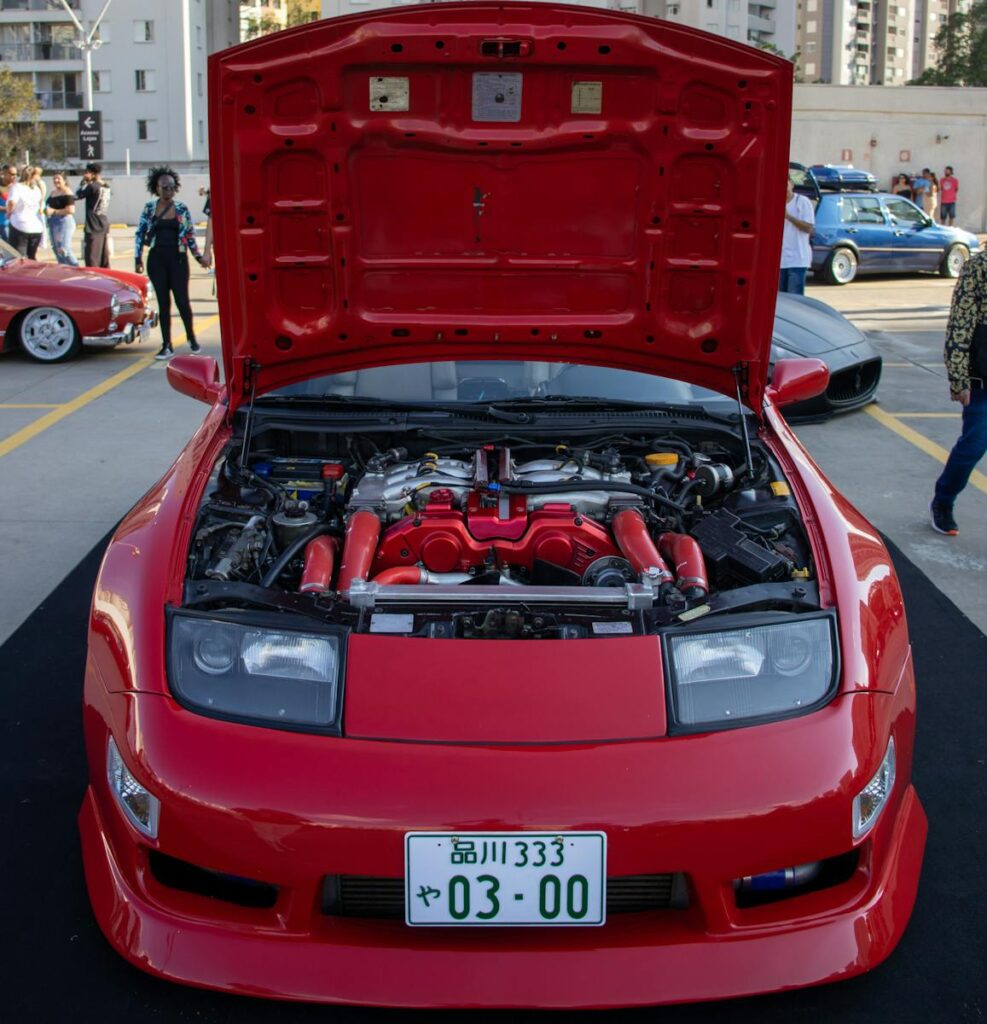 A vibrant red Nissan 300ZX with an open hood displayed at an urban car show.