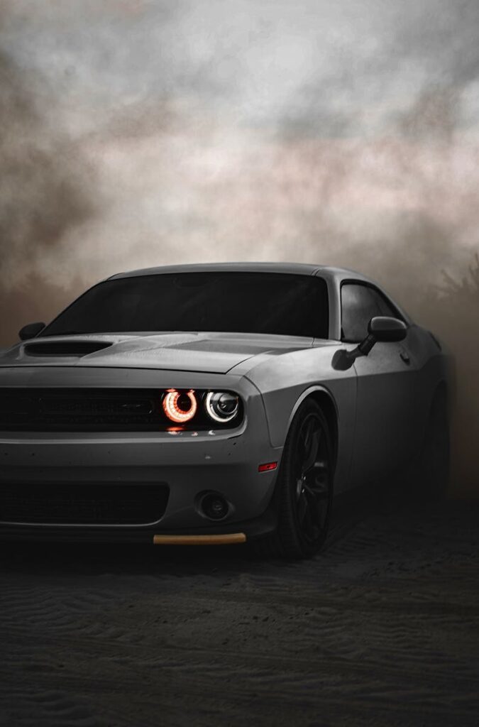 Dodge Challenger sports car in a dramatic, cloudy outdoor setting. Ideal for automotive enthusiasts.