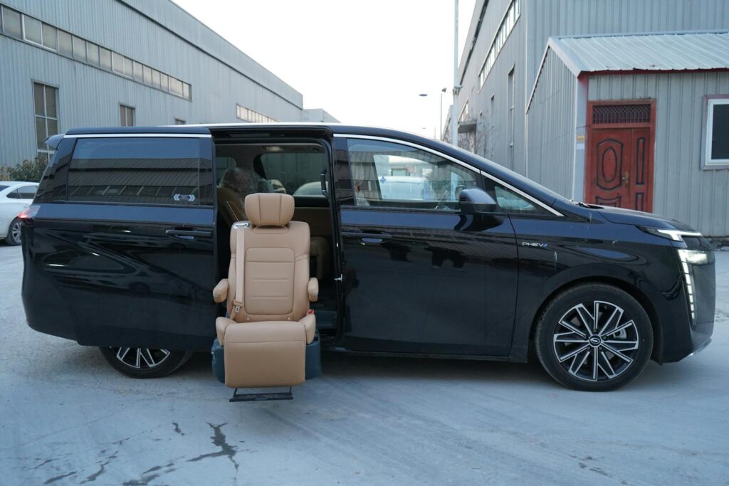 Black minivan parked outdoors with open door displaying an accessible seat feature on a cold winter day.