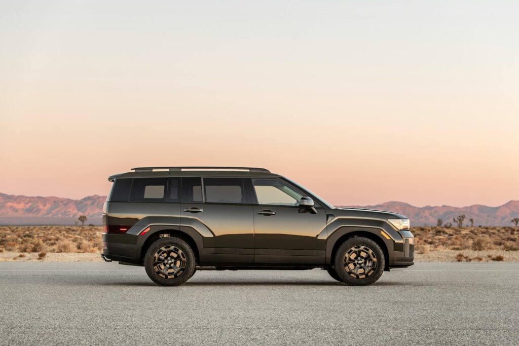 Side view of an SUV parked on a desert road during sunset, showcasing a scenic landscape.