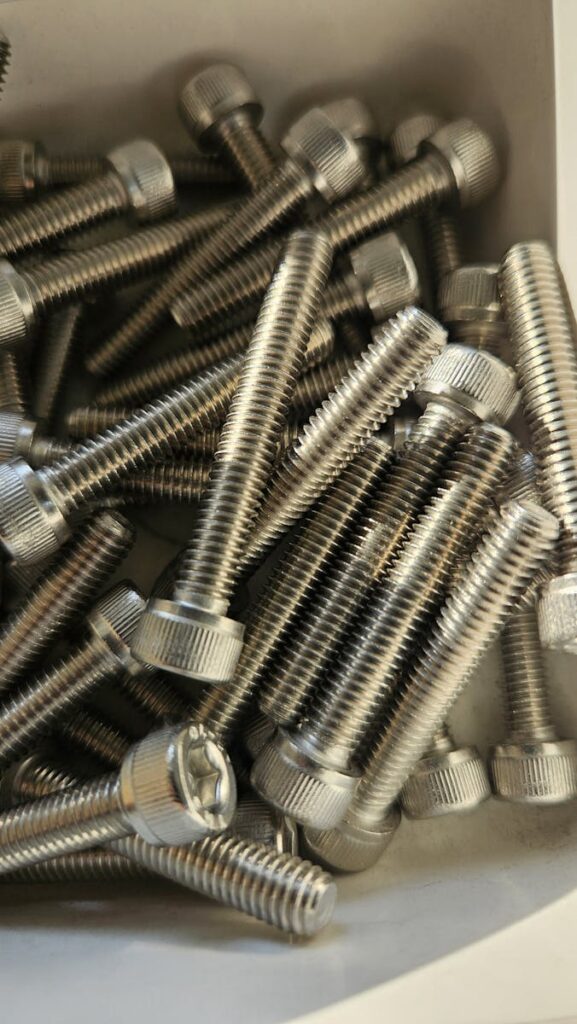 A detailed shot of stainless steel screws in a box, showcasing industrial hardware.