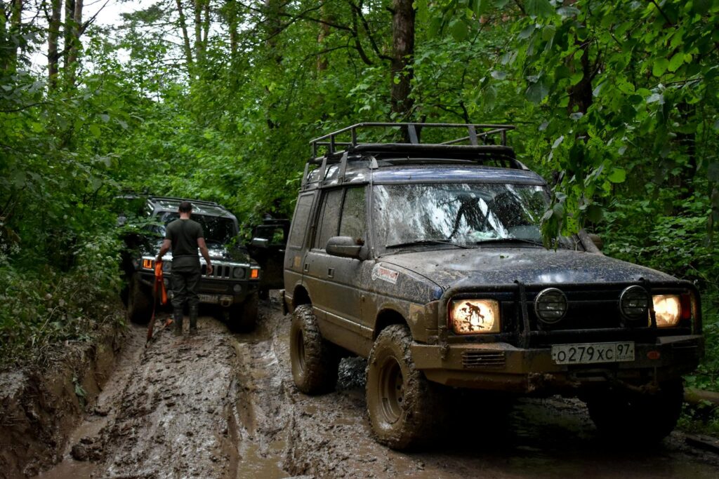 Off-road adventure with SUVs driving through muddy forest terrain.