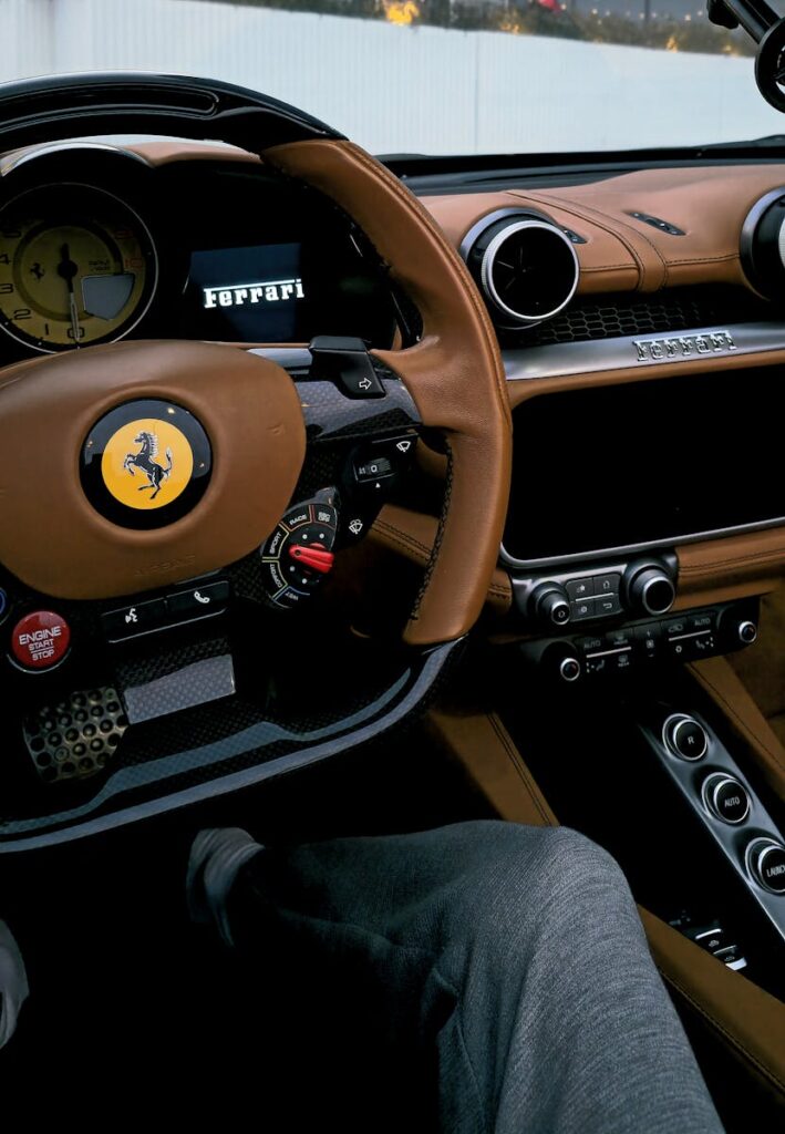 Experience the sleek design of a Ferrari with rich tan leather interior and modern controls.