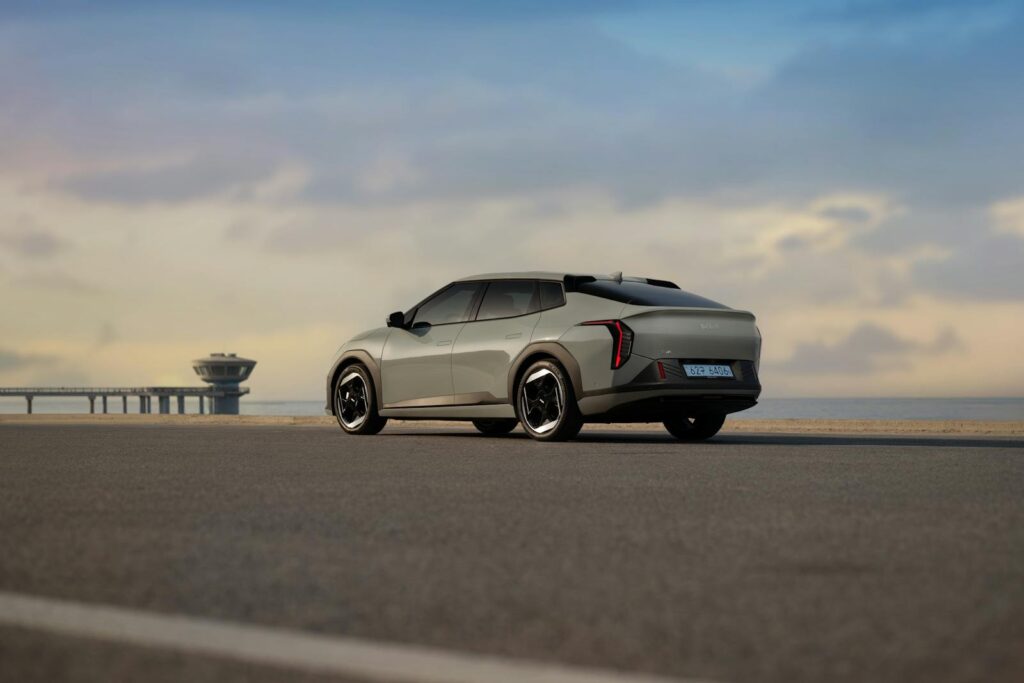 A modern electric vehicle parked on a coastal road, featuring a scenic view of the sea and sky.