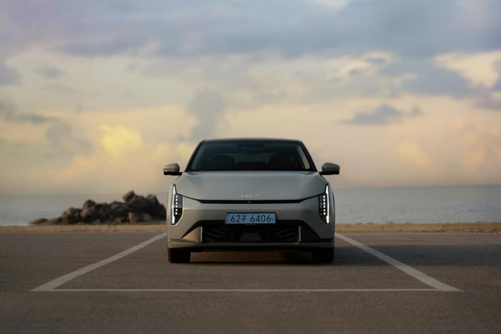 Front view of a stylish car parked by the ocean at sunset, showcasing modern automotive design.