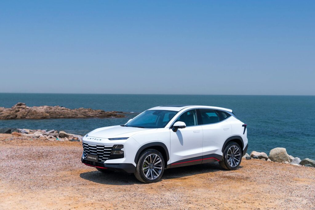 Elegant white SUV parked by the sea on a clear sunny day, perfect for coastal adventures.