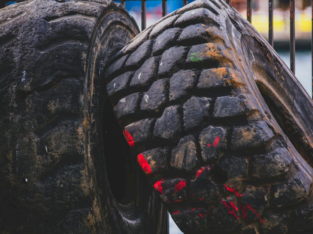 Detailed view of old, worn truck tires with visible red paint marks in an outdoor industrial setting.