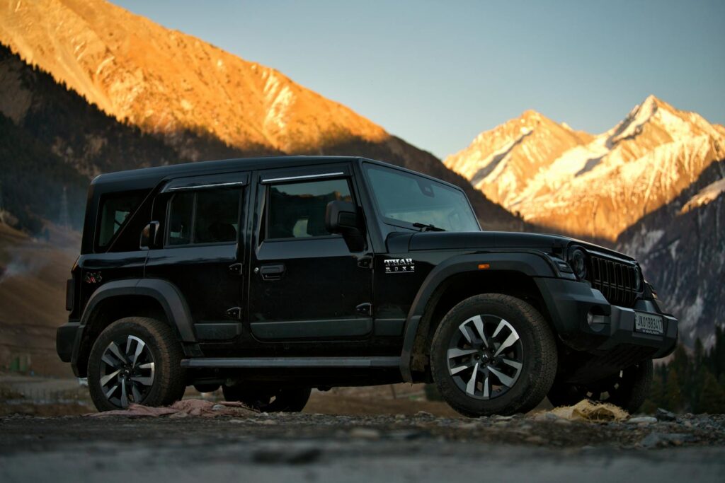 Black Mahindra Thar parked against the breathtaking backdrop of Sonamarg's alpine mountains during sunset.