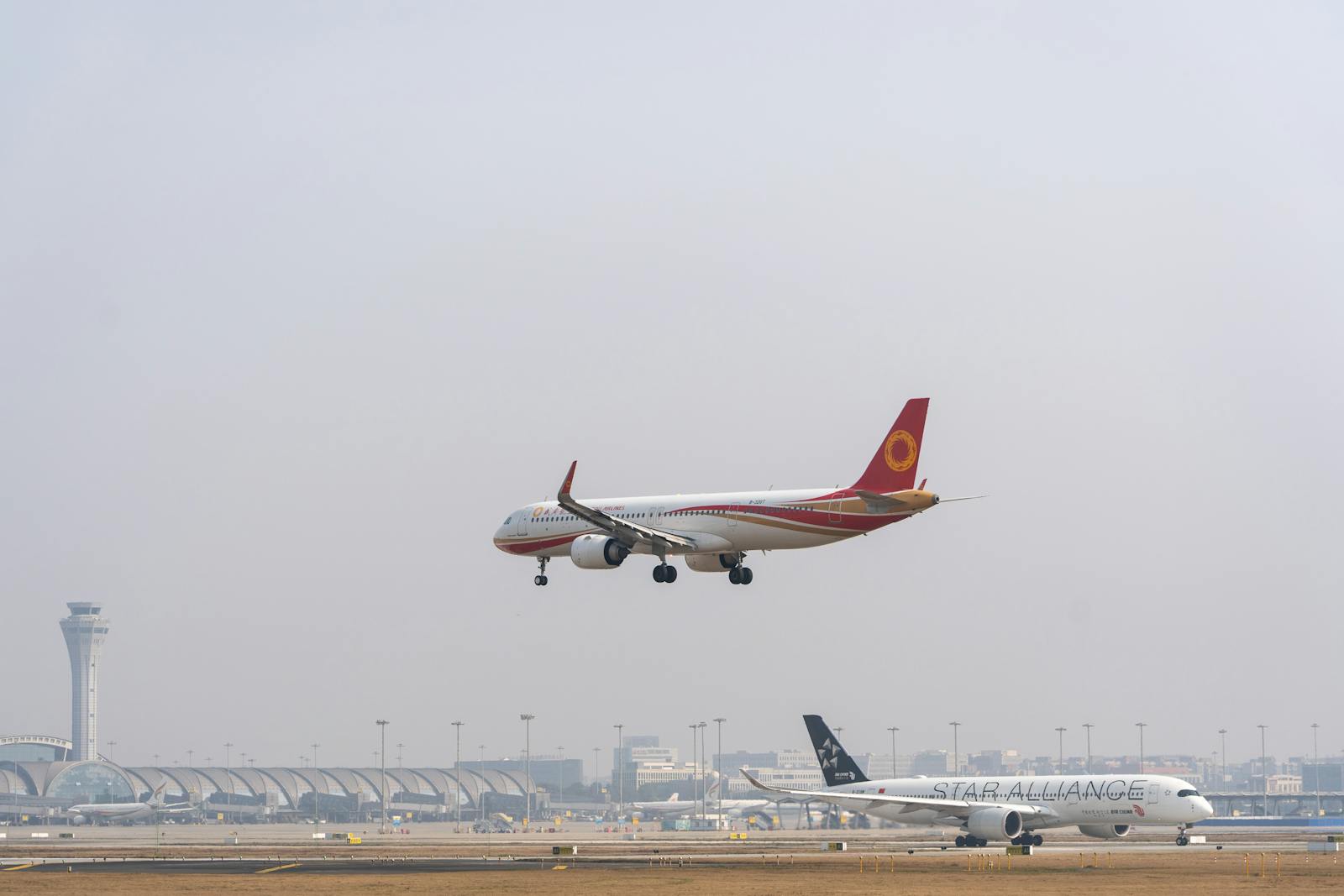 A commercial airplane landing at a bustling international airport with clear skies.