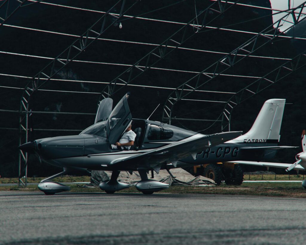 Modern light aircraft parked in an open hangar with visible framework, highlighting transportation.