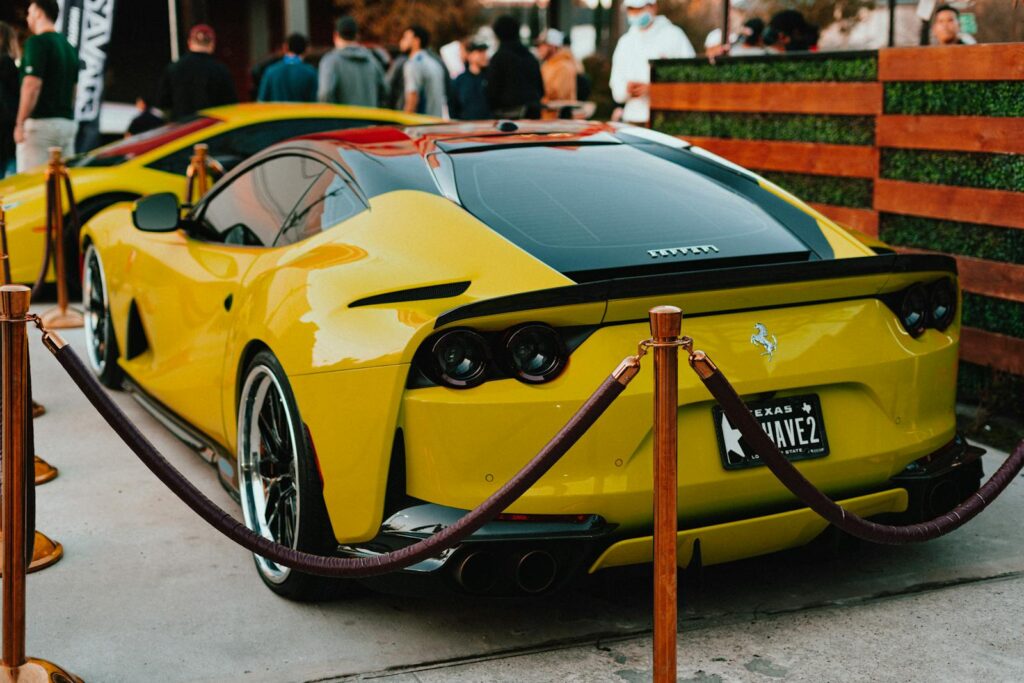 Vibrant yellow Ferrari showcased outdoors at a luxury car event.