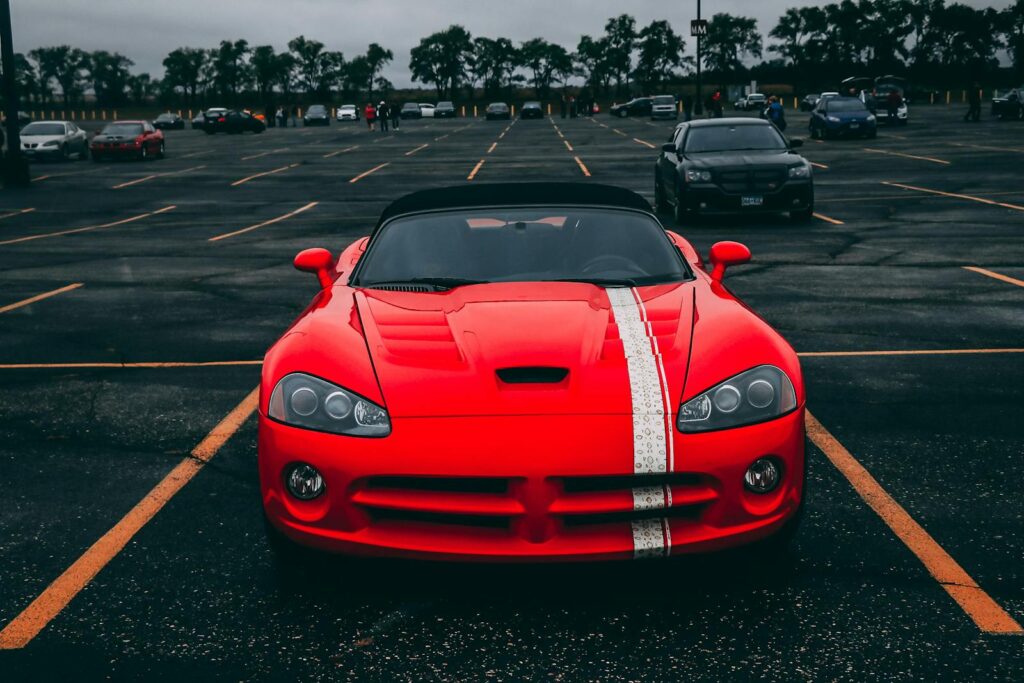 Vibrant red sports car parked in an empty lot with overcast skies.