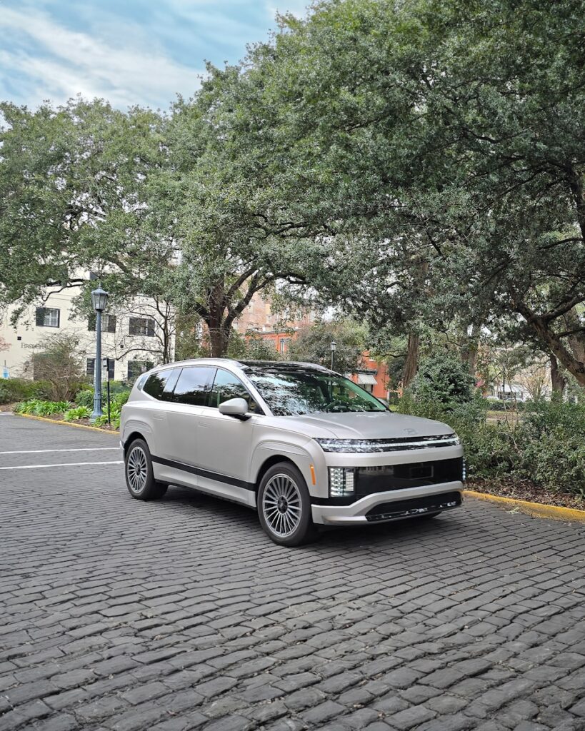 A silver suv parks on a cobblestone road.