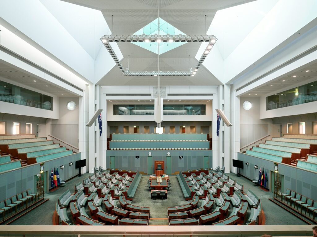 Interior of an empty parliamentary chamber with tiered seating.
