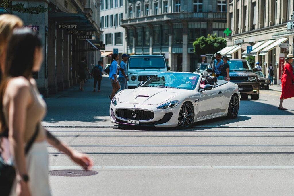 a white sports car driving down a city street