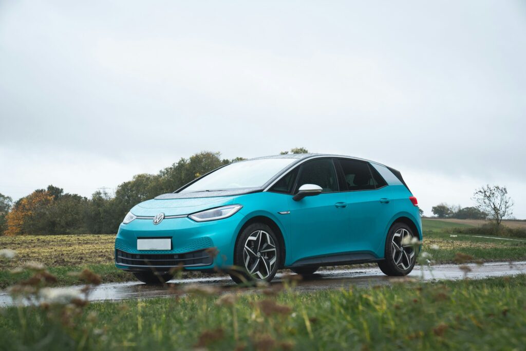 A teal electric car parked on a wet road