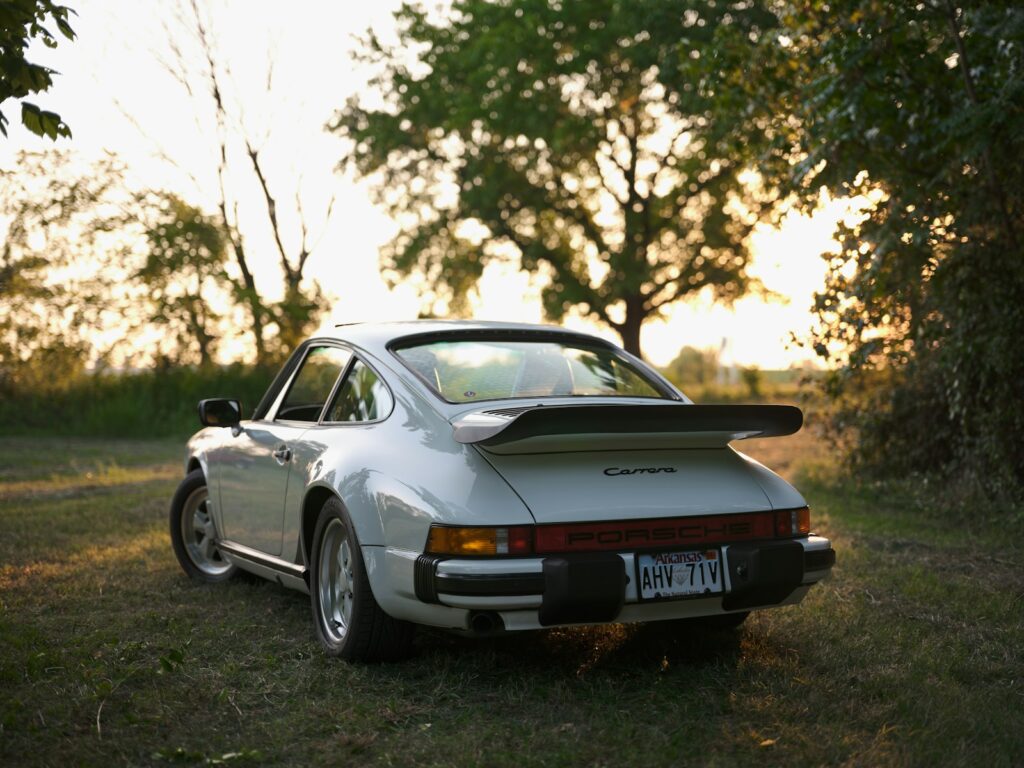 A classic white porsche parks in the meadow.