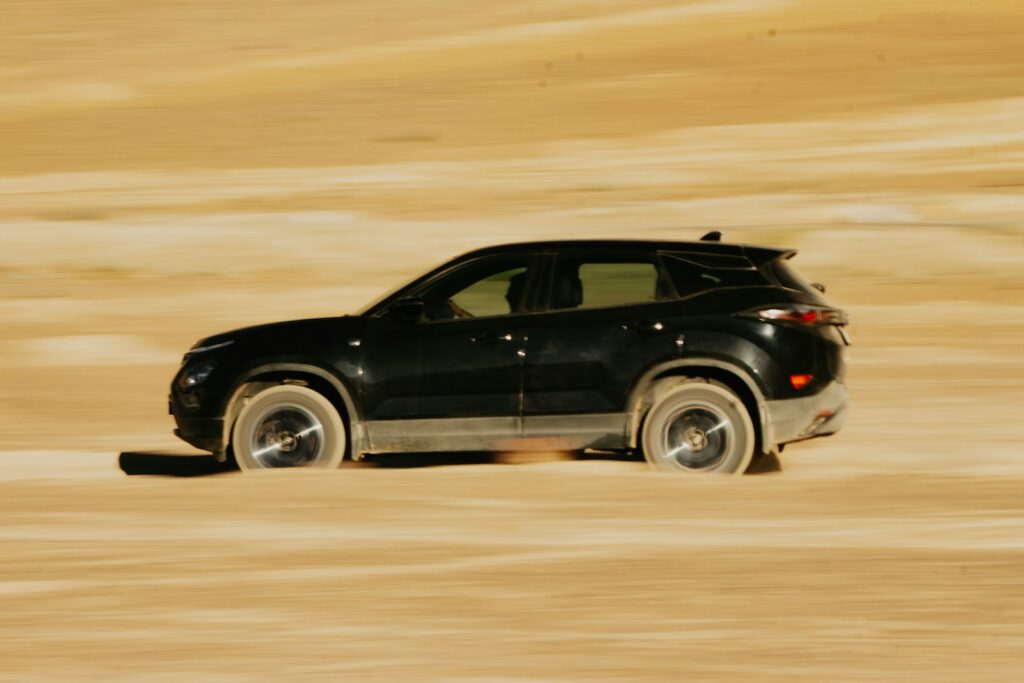 A black car driving through a sandy area