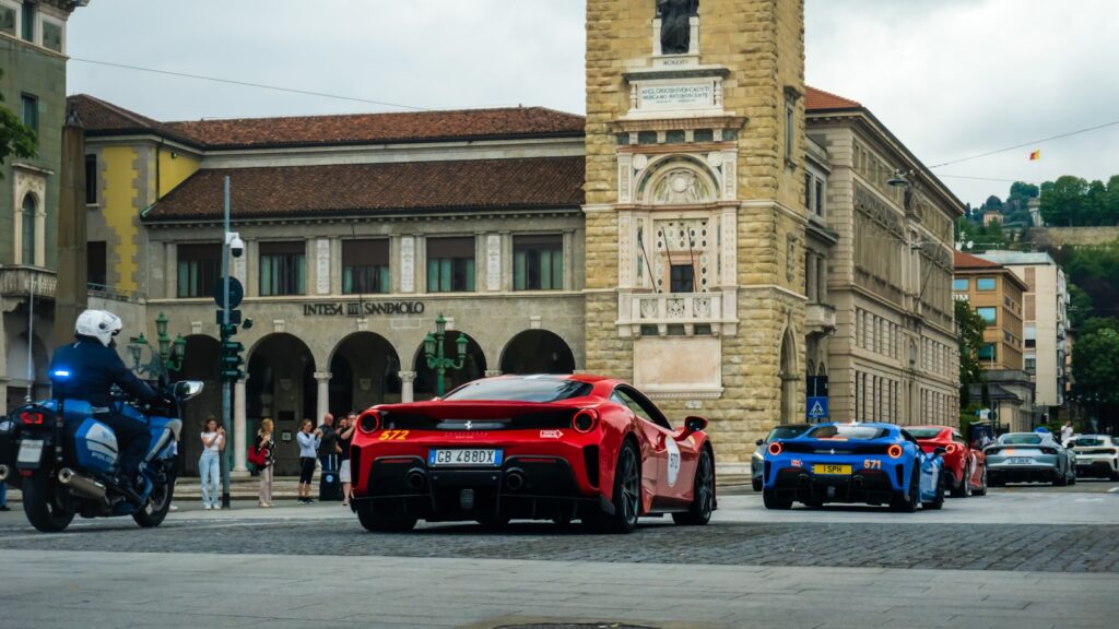 Red sports car leads others down city street