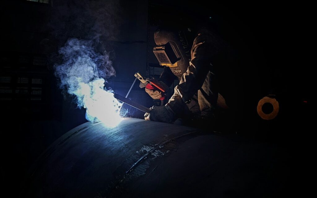 a welder working on a pipe in the dark