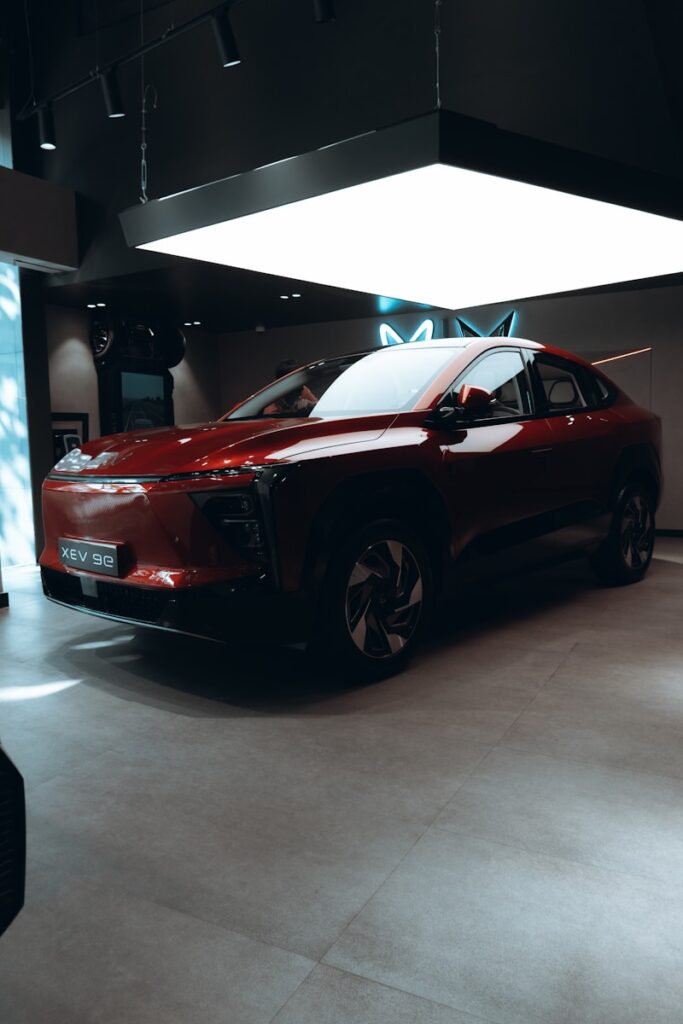 A sleek, dark red car is parked indoors.