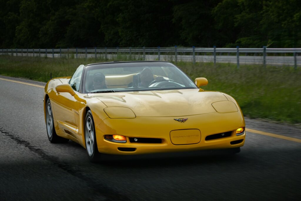 A yellow convertible sports car driving on a road.