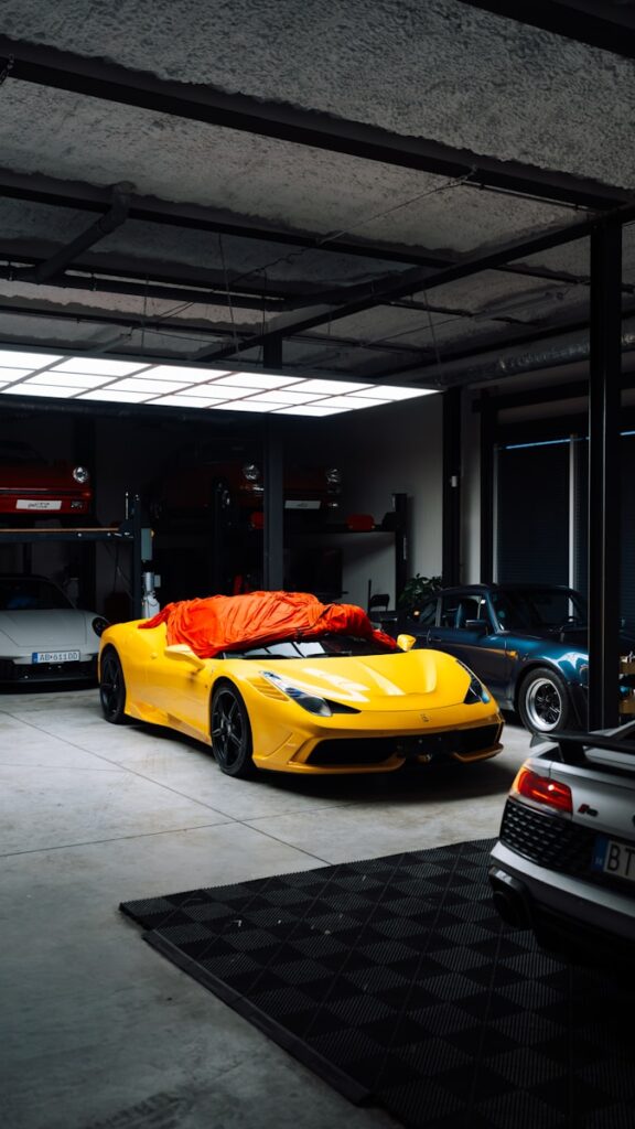 Yellow sports car covered with orange tarp in garage.