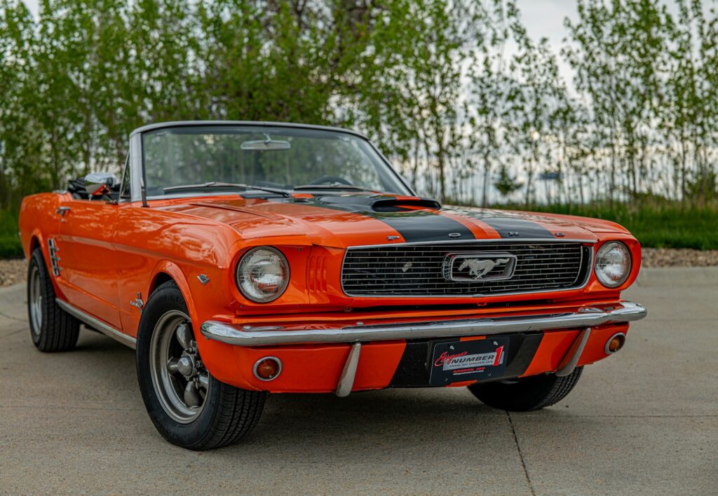 An orange and black mustang parked in a parking lot