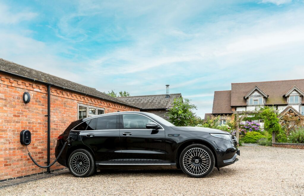Black electric car charging next to brick building