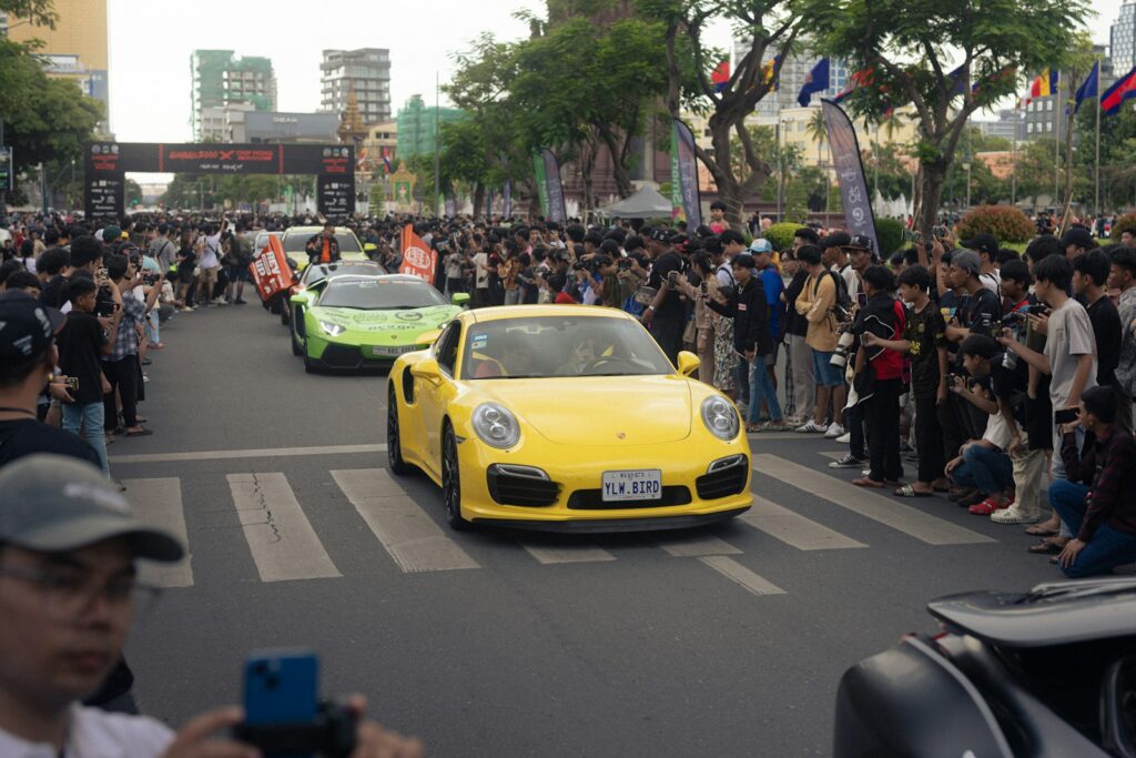 Yellow porsche leads a street parade of cars.