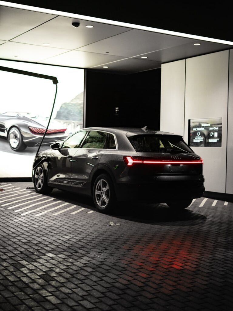 Dark grey audi e-tron parked indoors with illuminated taillights.