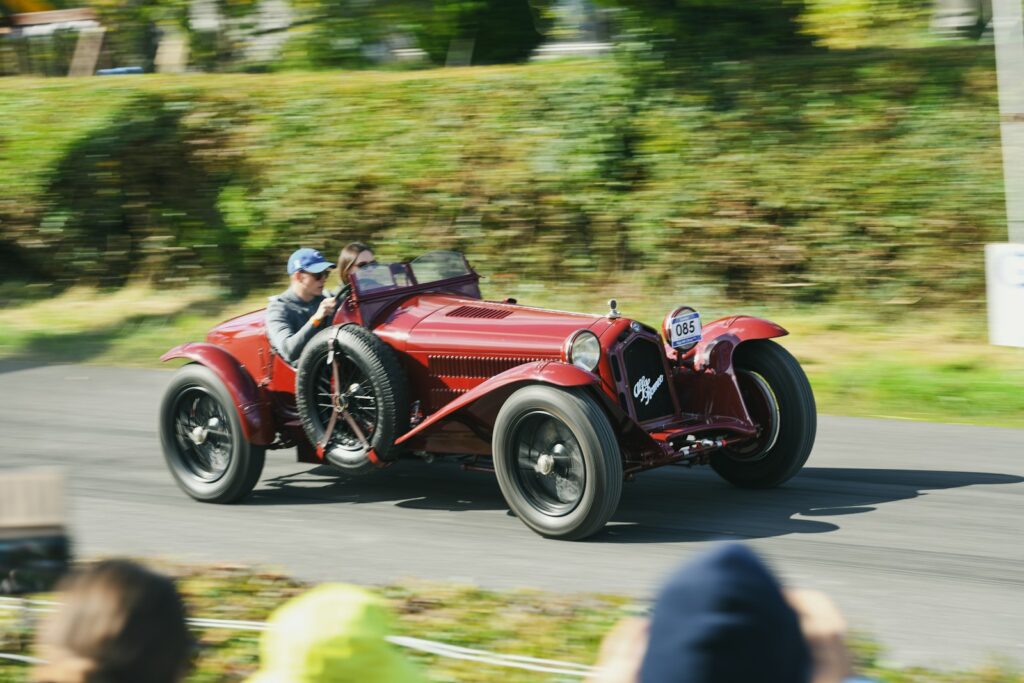 Vintage red convertible car racing on a road.