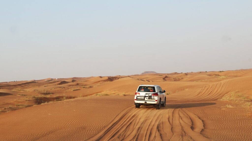 A truck driving down a dirt road in the desert