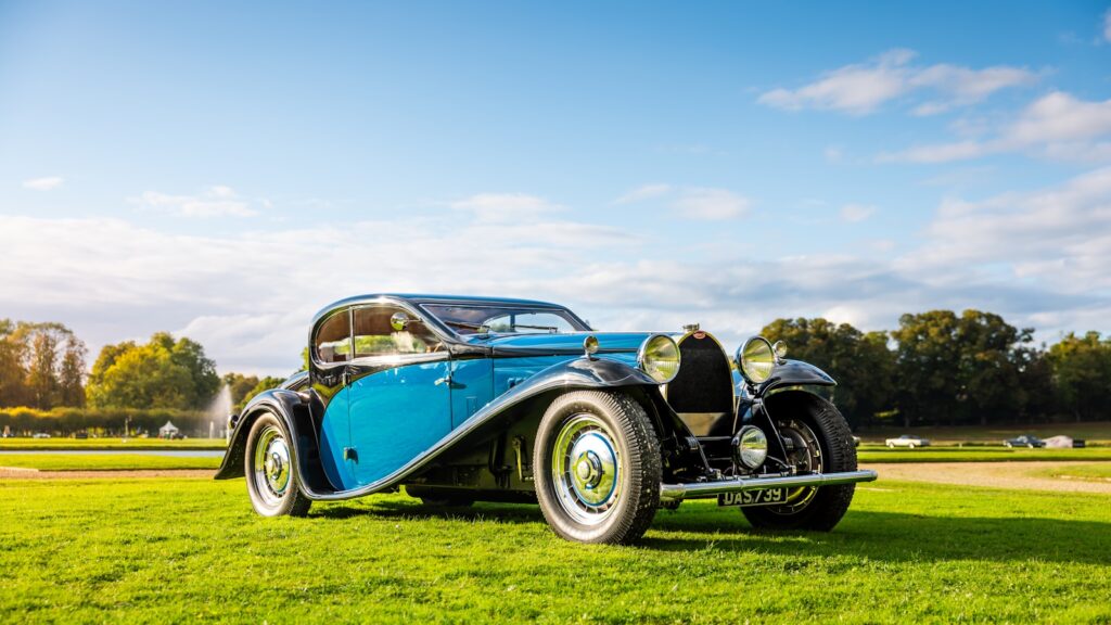A classic bugatti car parked on green grass.
