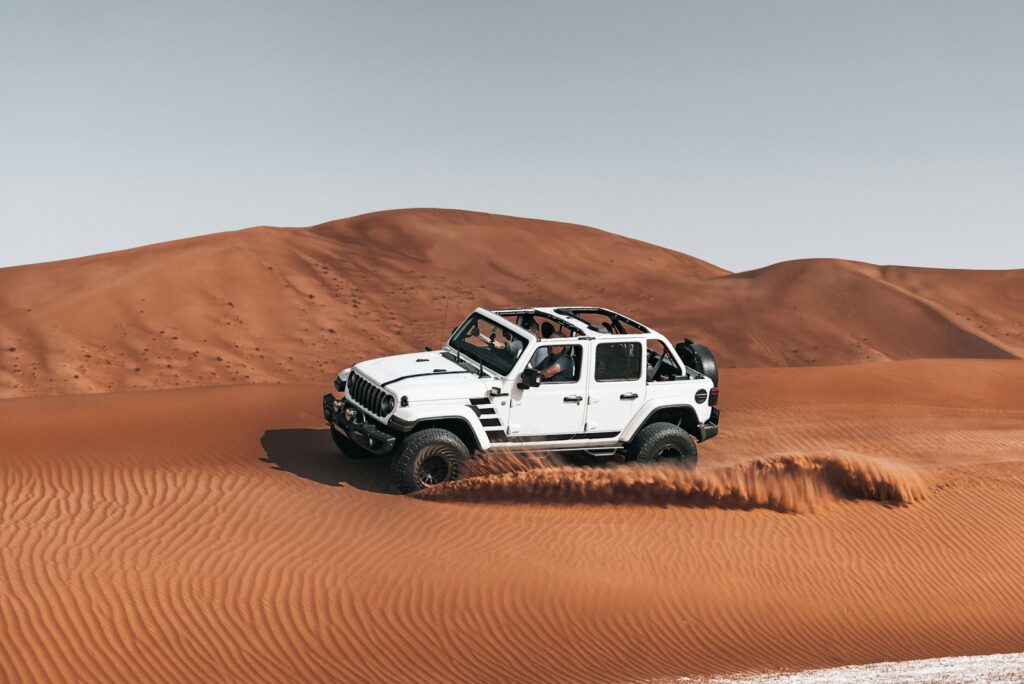 White jeep driving through desert sand dunes