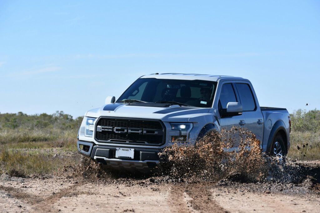 a silver truck is driving through the mud