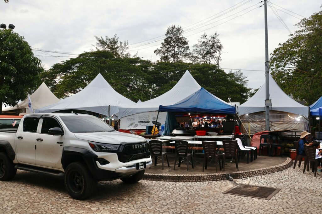 White pickup truck parked near outdoor market stalls