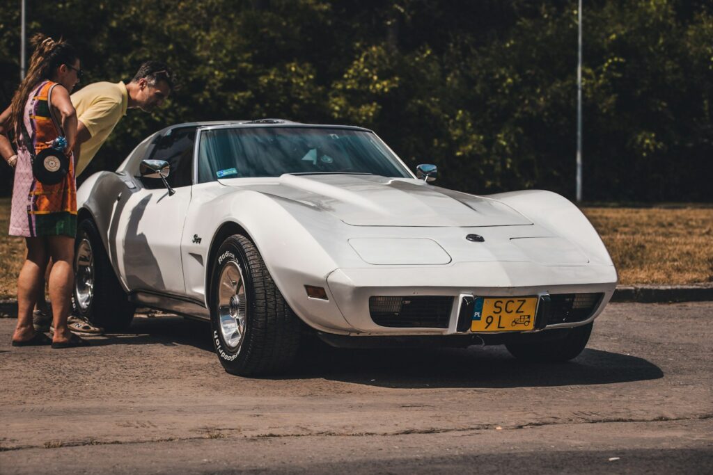 a man and a woman standing next to a white sports car