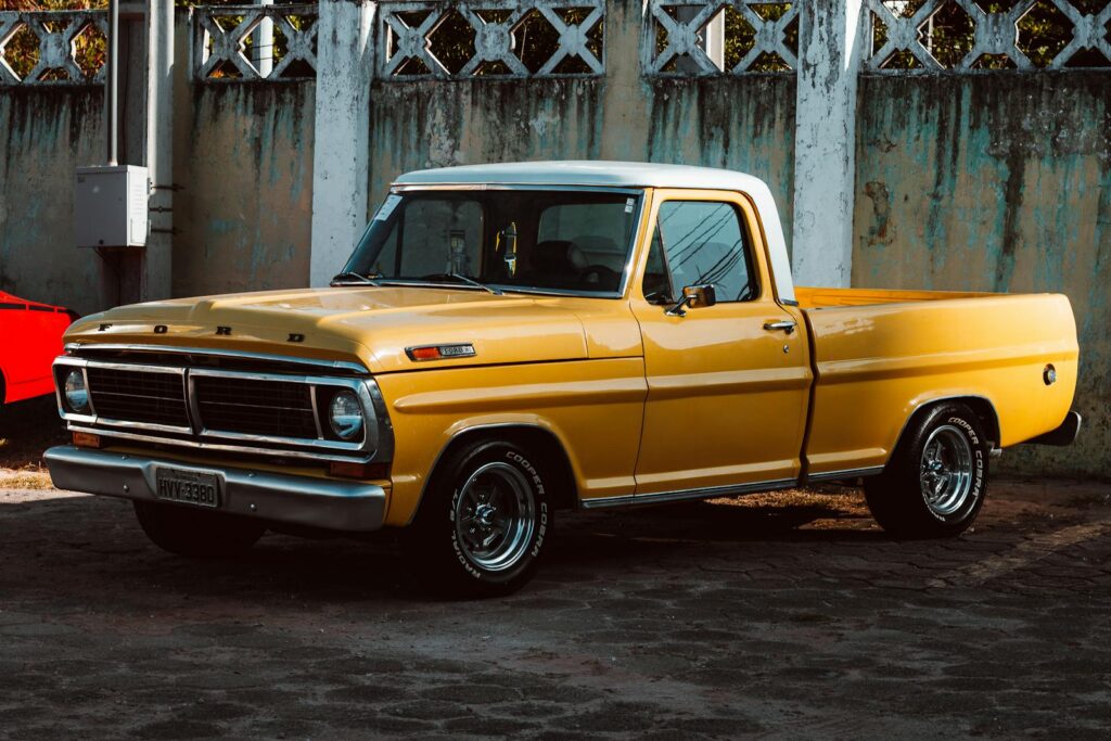 Vintage yellow Ford pickup truck parked against a concrete wall in Fortaleza, Brazil.