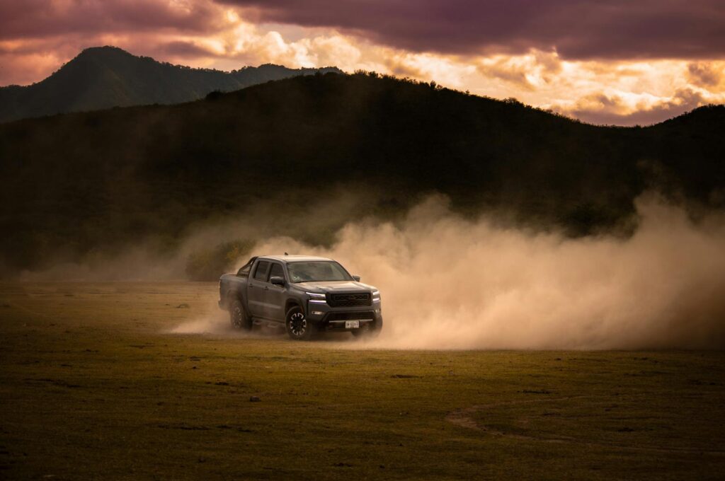 Pick-up truck drifting through dust in a picturesque Mexican landscape at sunset.
