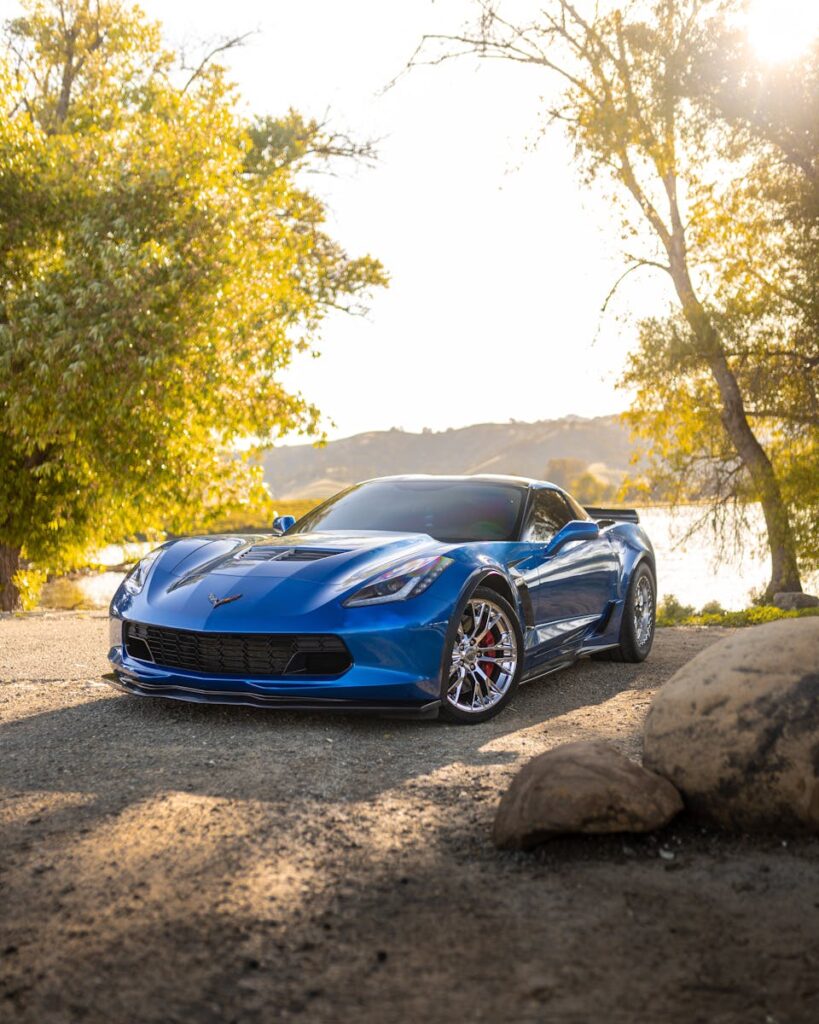 Stunning blue Chevrolet Corvette Z06 parked by a serene lake in rural setting.