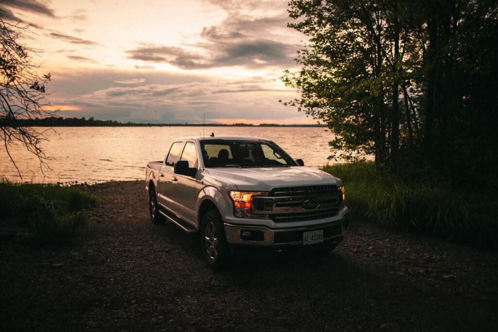Scenic view of a Ford F-150 truck by a lakeshore in Quebec City at sunset, showcasing the beauty of rural Canada.