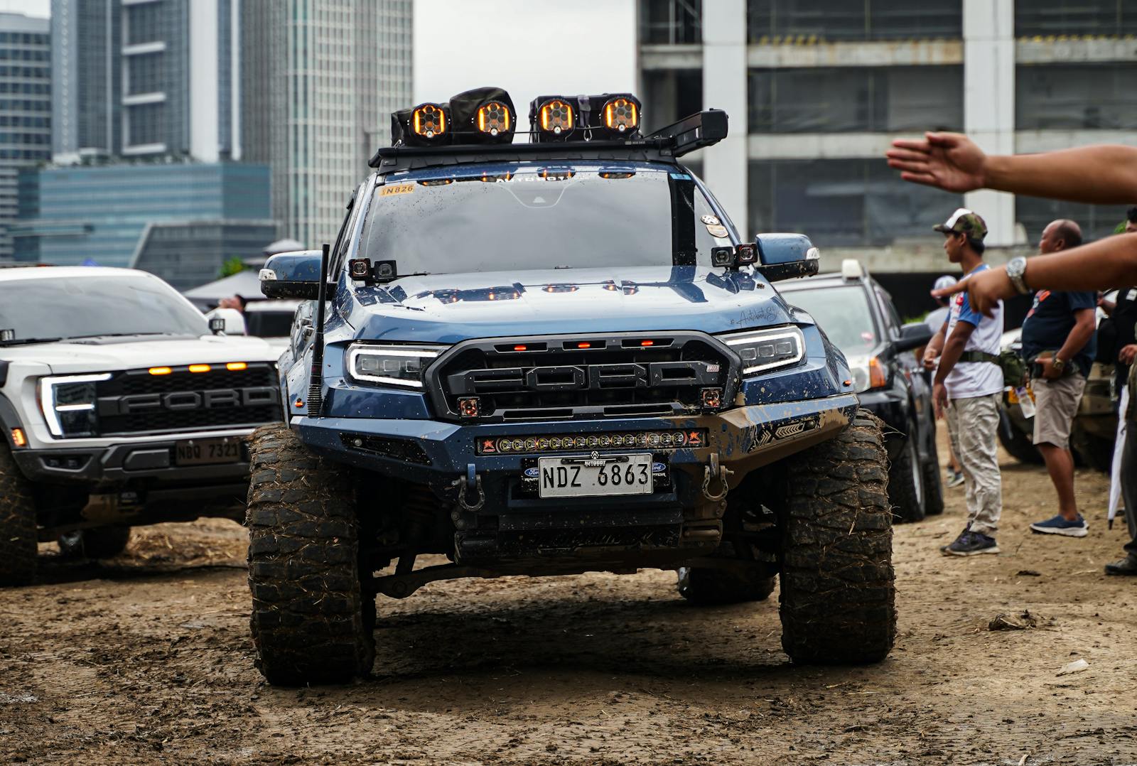 Dynamic shot of off-road trucks in a city setting, showcasing rugged vehicles and urban landscape.