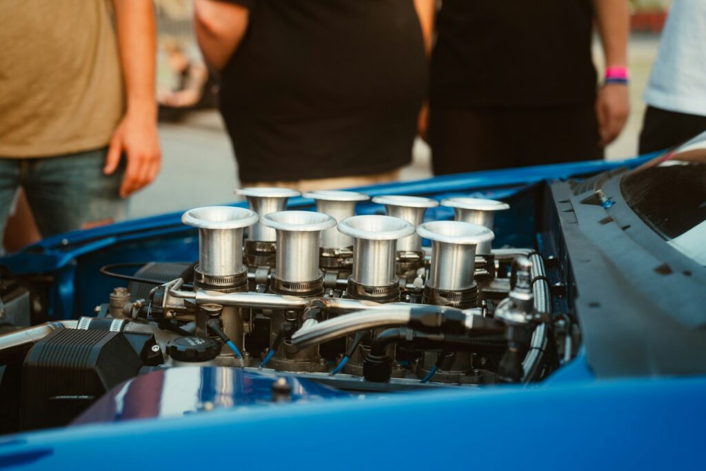 A group of people standing around a blue sports car
