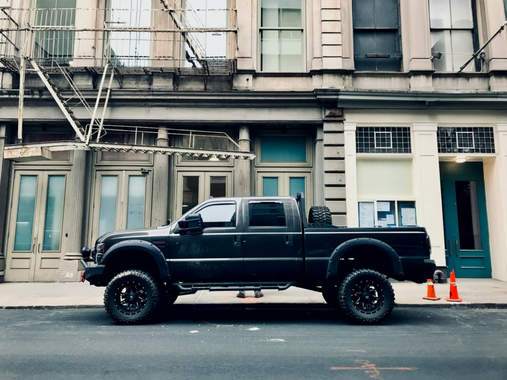 Black pickup truck parked in front of urban building, showcasing rugged design and tires.