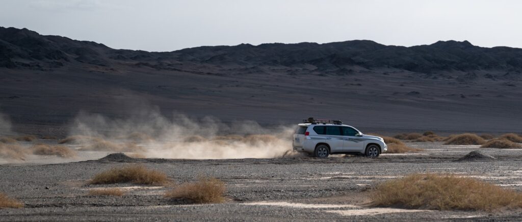 A white truck driving down a desert road