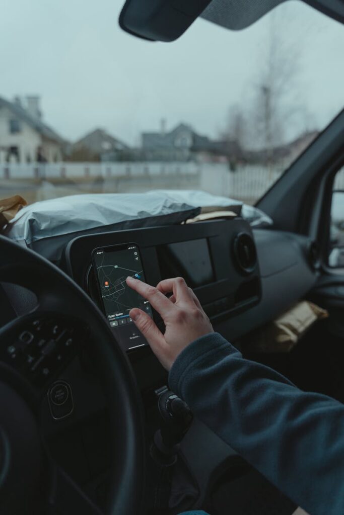 Hand using smartphone GPS inside car on a cloudy day. Technology and travel concept.