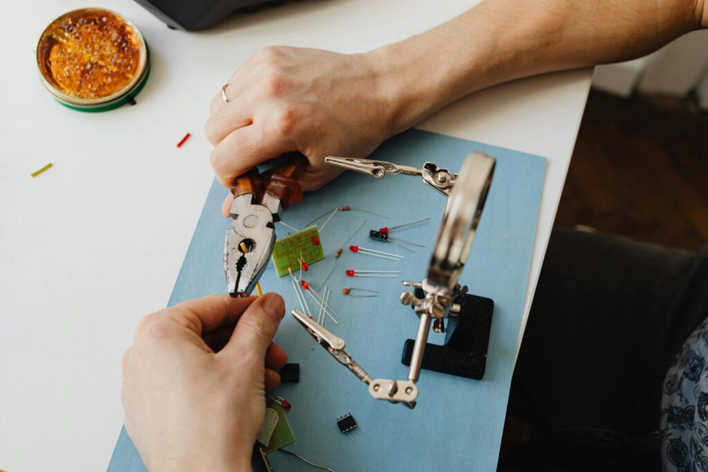 Close-up view of hands using tools to assemble electronic components with precision on a desk.